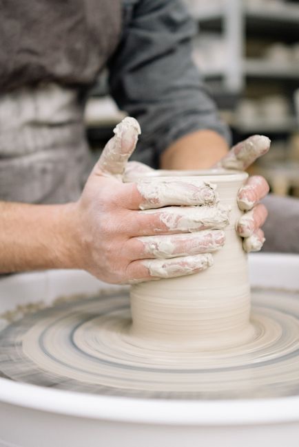Hands shaping a pot on a wheel