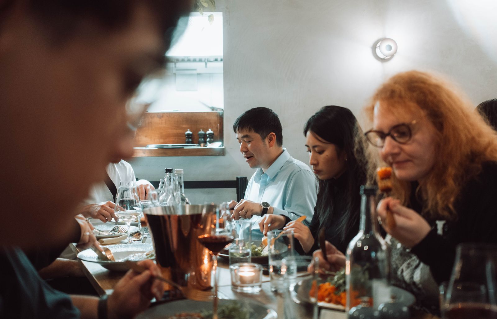 A diverse group sharing a meal together around a restaurant table