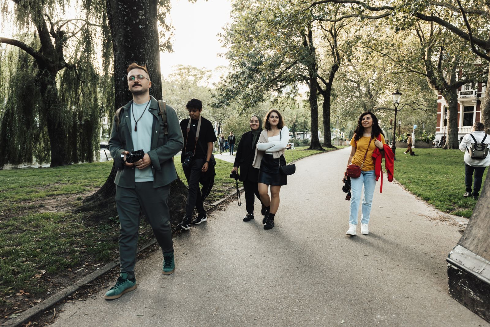 A host leading a group of photographers through a city park