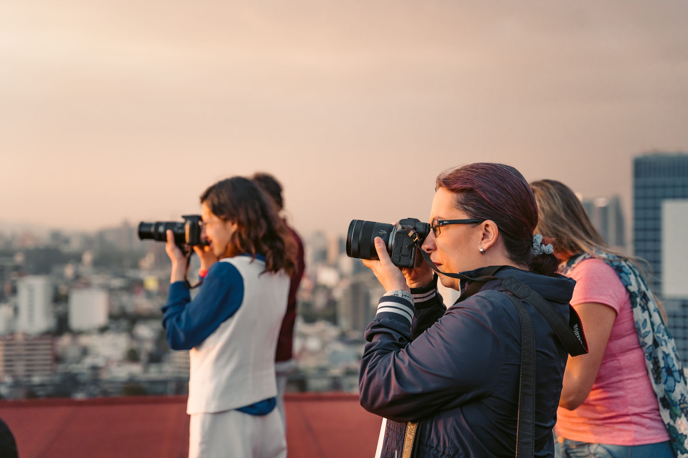 People taking photos on a rooftop at sunset