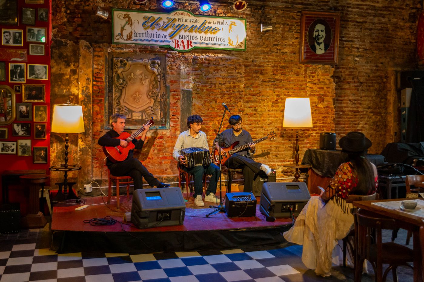Three musicians playing in a cosy brick-walled bar
