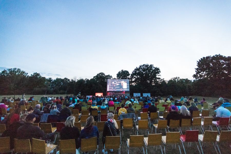 An audience at an outdoor film screening in a park