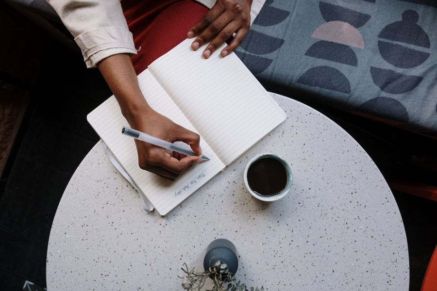A notebook and pen on a café table beside a coffee