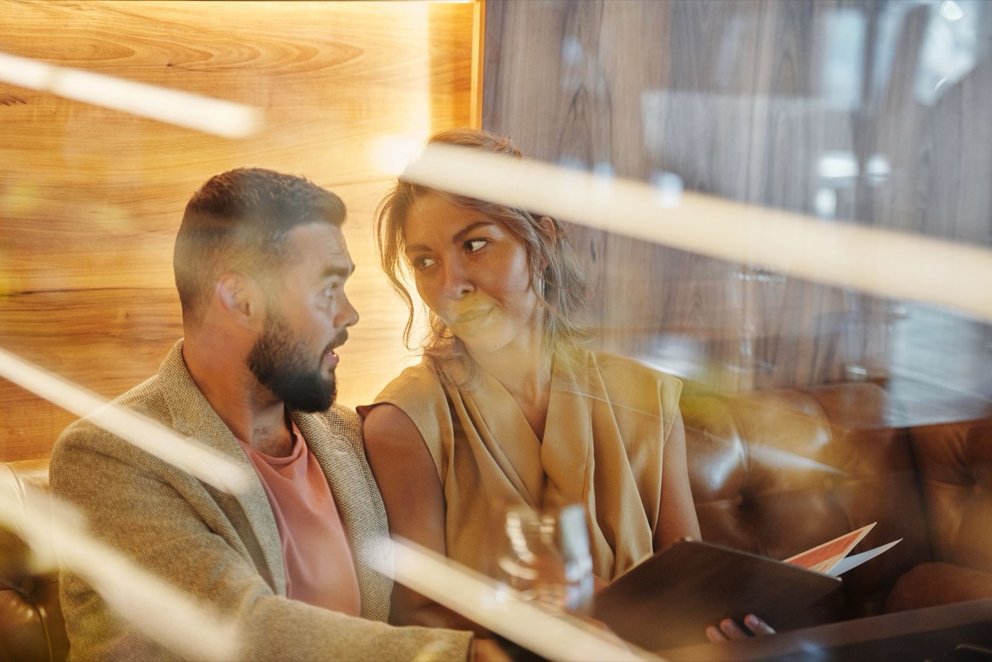 A man and a woman talking closely at a bar table