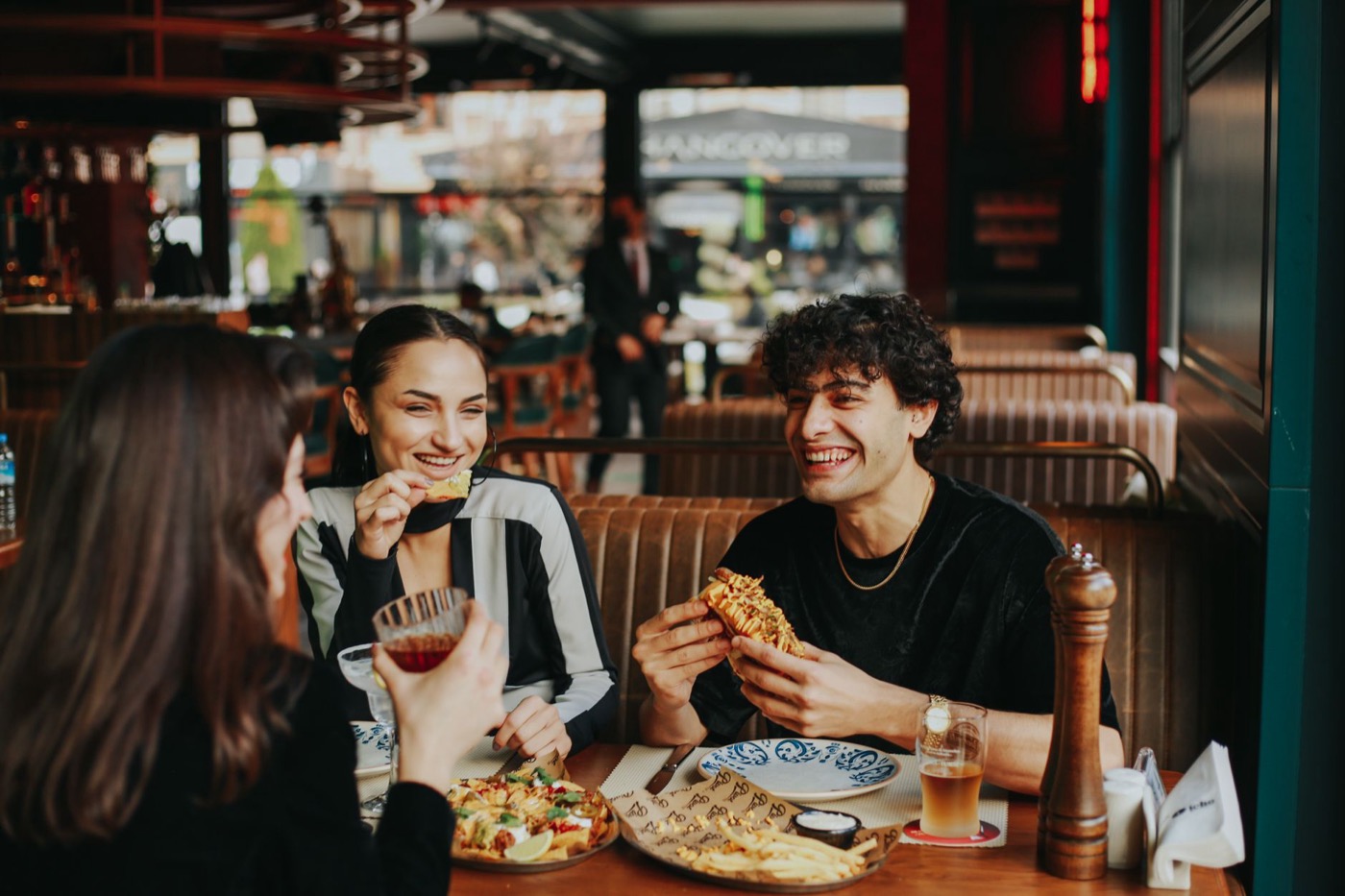 Three friends laughing over lunch at a restaurant table