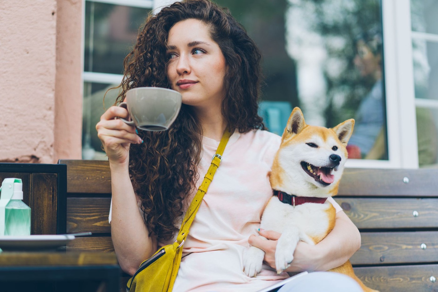 A woman with a coffee and her dog at an outdoor café table