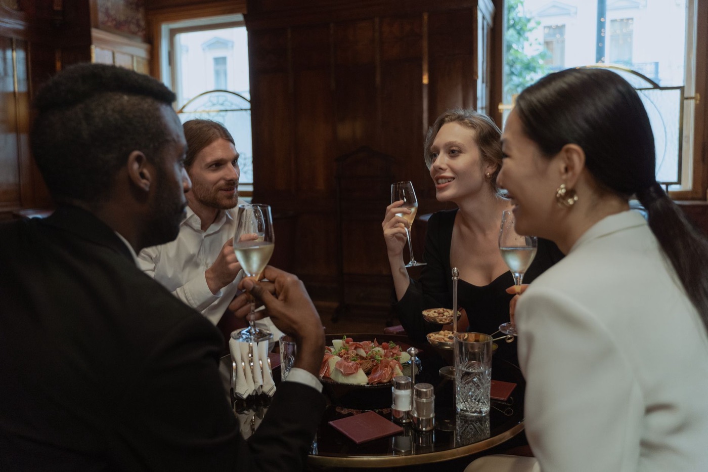 Four friends raising their glasses at a restaurant table