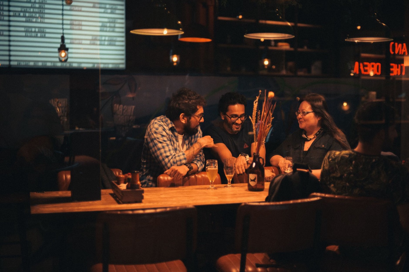 Three people talking over drinks at a table in a dark bar